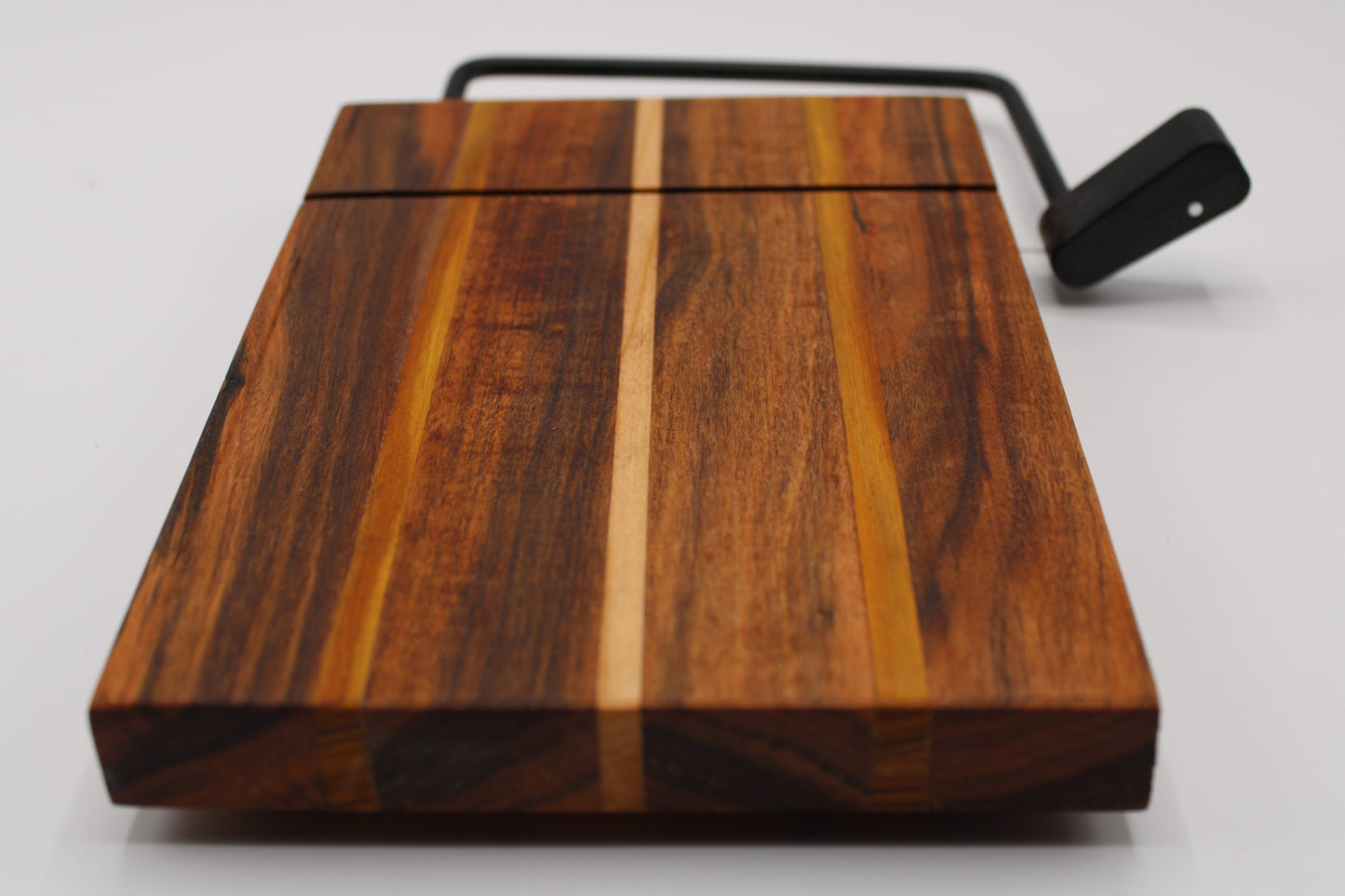 Wooden cheese cutting board with slicer on a light gray background