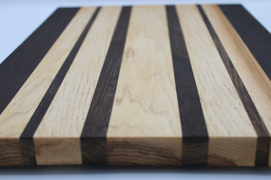 Wooden cutting board with black and natural wood stripes on a white background