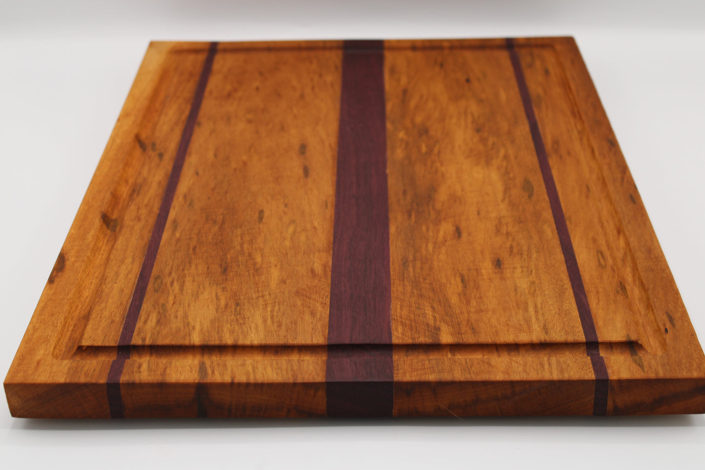 Wooden cutting board with purpleheart inlay on a white background