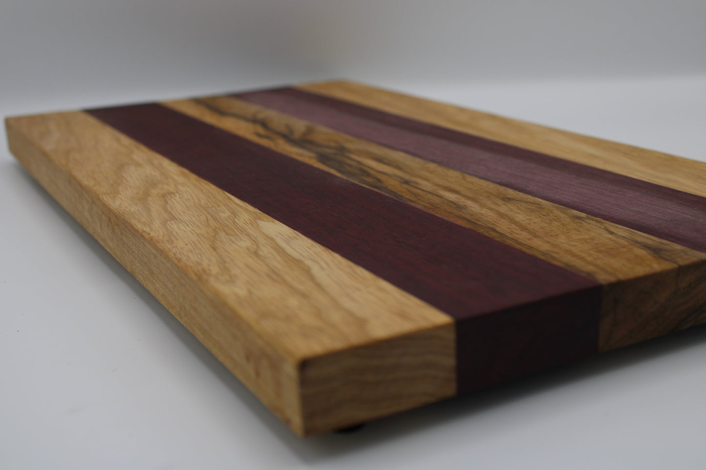 Wooden cutting board with purple and brown stripes on a white background
