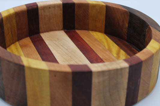 Wooden bowl with multicolored striped pattern on a light background