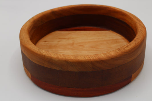 A round wooden bowl with a layered inlay design, featuring a light tan cherry wood top, a dark reddish-brown middle band, and a reddish-brown outer band, shown on a light gray background.