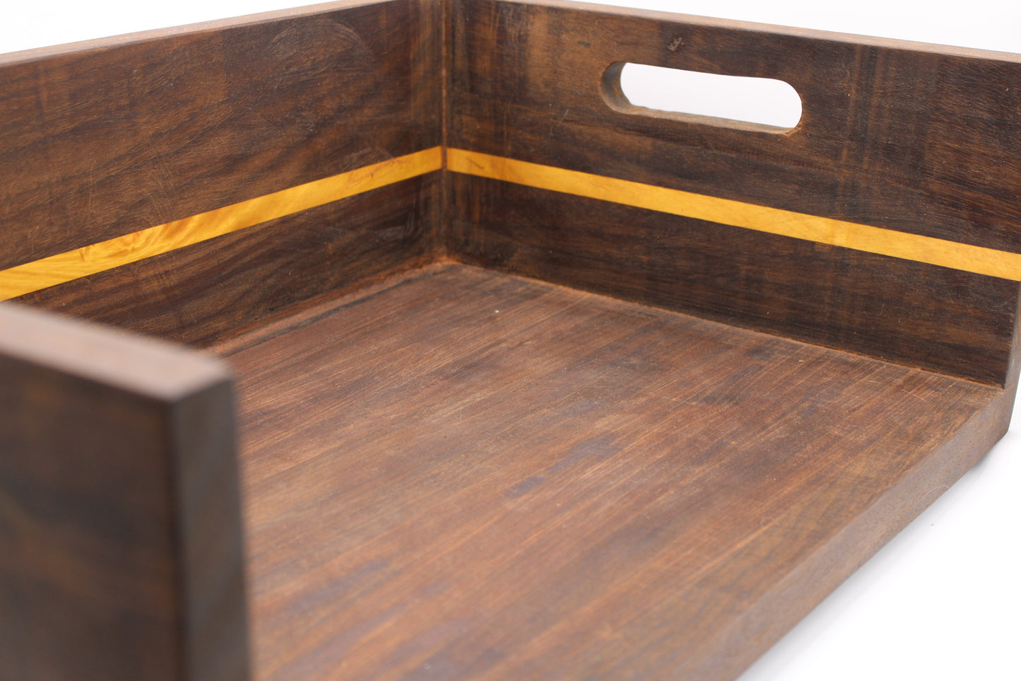 Close-up of a dark brown wooden serving tray with a yellow inlay stripe and a cutout handle on the back panel, shown on a white background.