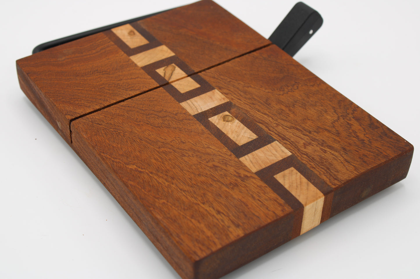 A wooden cheese board with a geometric inlay pattern, featuring a dark brown wood body, a lighter natural wood stripe, and a black handle on a white background.