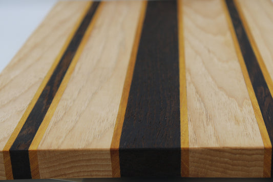 Striped wooden cutting board with light, dark and orange stripes