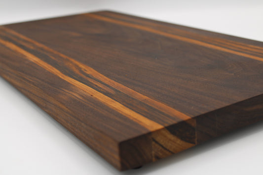 Wooden cutting board with a dark brown finish on a white background