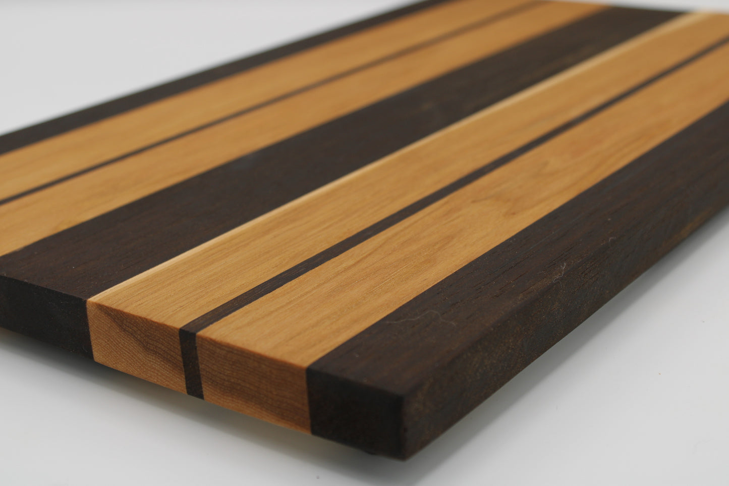 Wooden cutting board with alternating dark and light brown stripes on a white background
