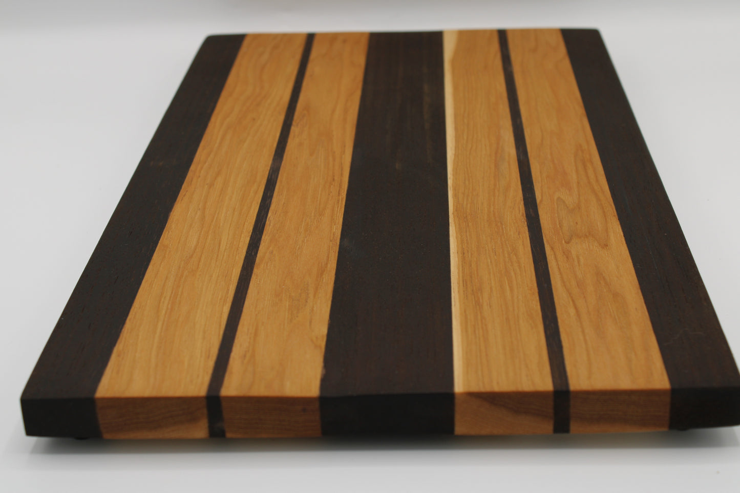 Wooden cutting board with black and brown stripes on a white background