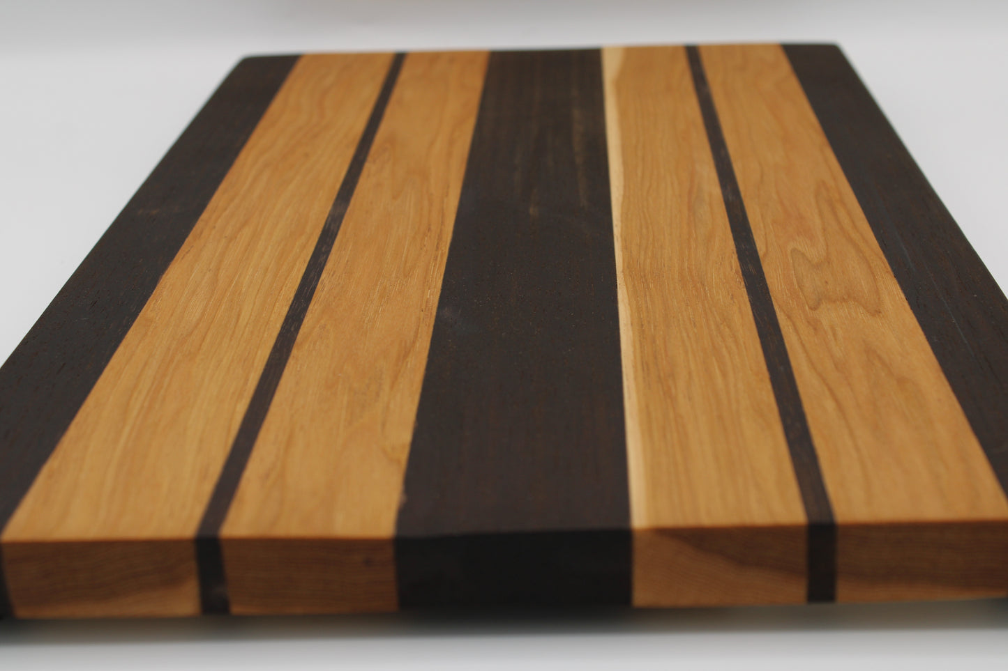 Wooden cutting board with black and brown stripes on a white background