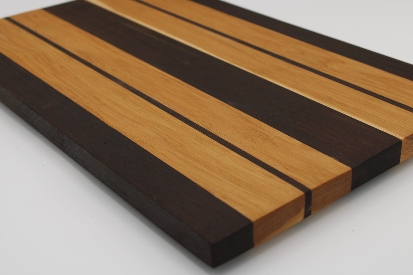Wooden cutting board with black and brown stripes on a white background