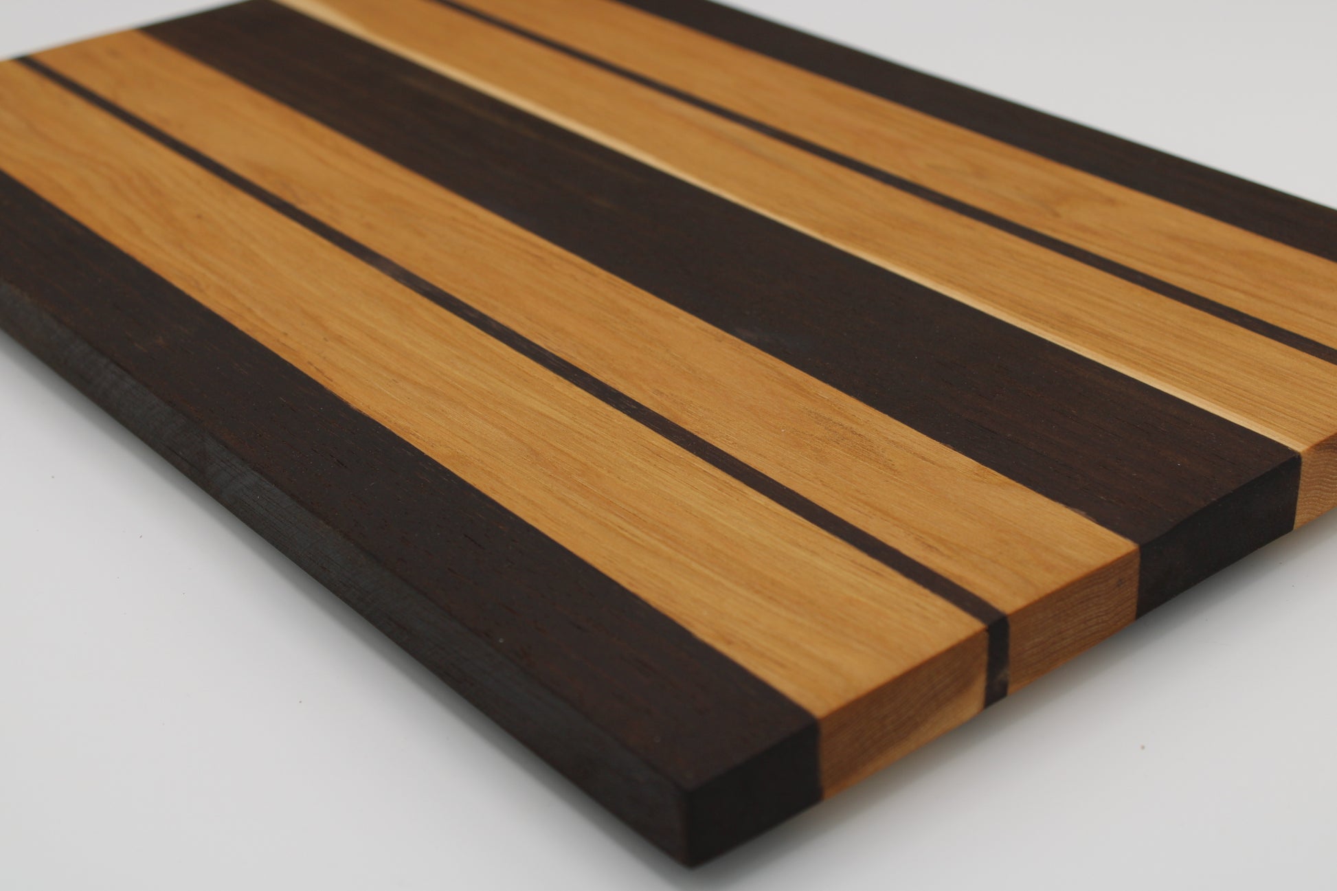 Wooden cutting board with black and brown stripes on a white background