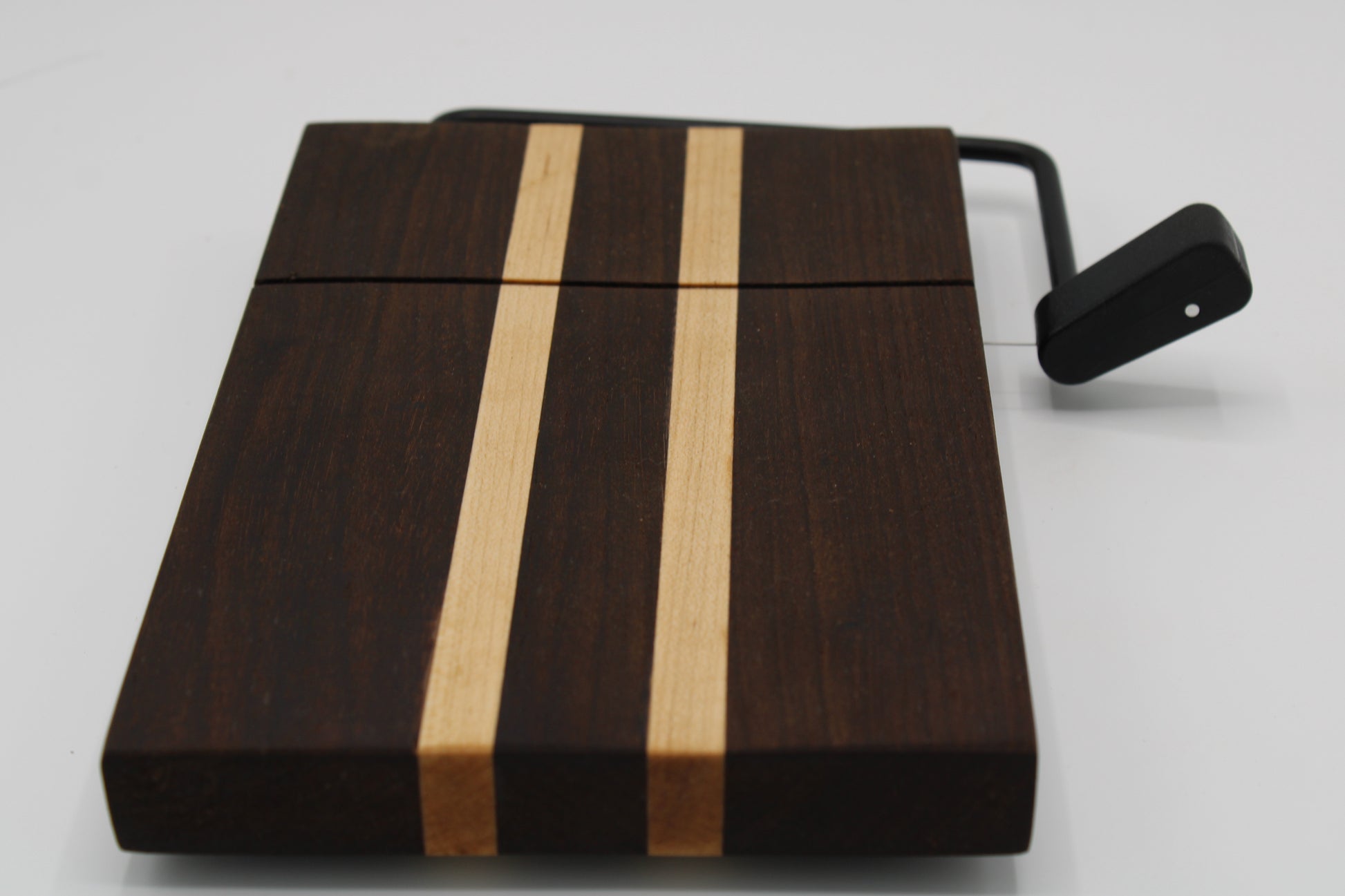 Wooden cheese board with a black slicer on a white background
