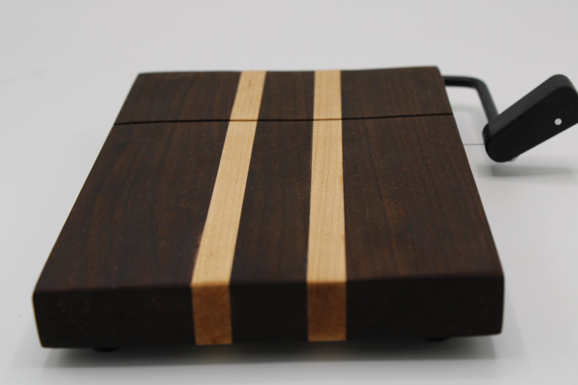Wooden cheese board with a black slicer on a white background