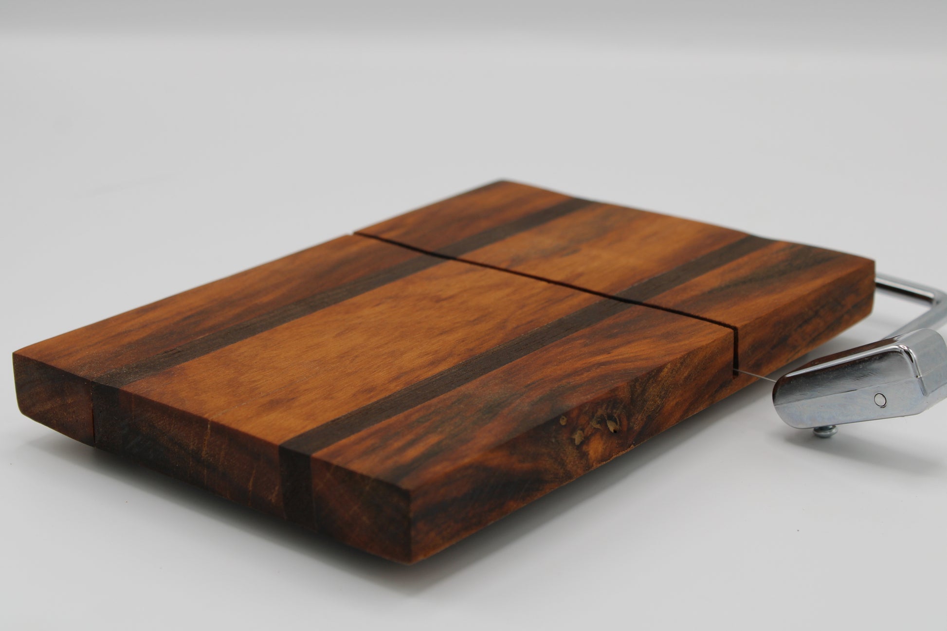 Wooden cheese board with a silver slicer on a white background