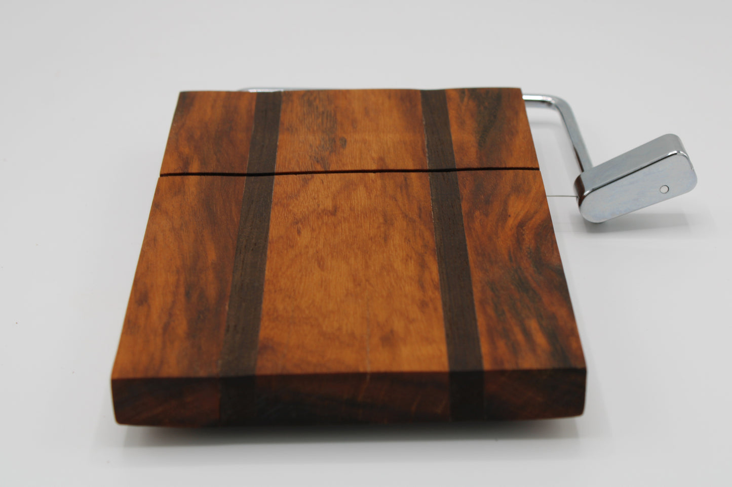 Wooden cheese board with a silver slicer on a white background