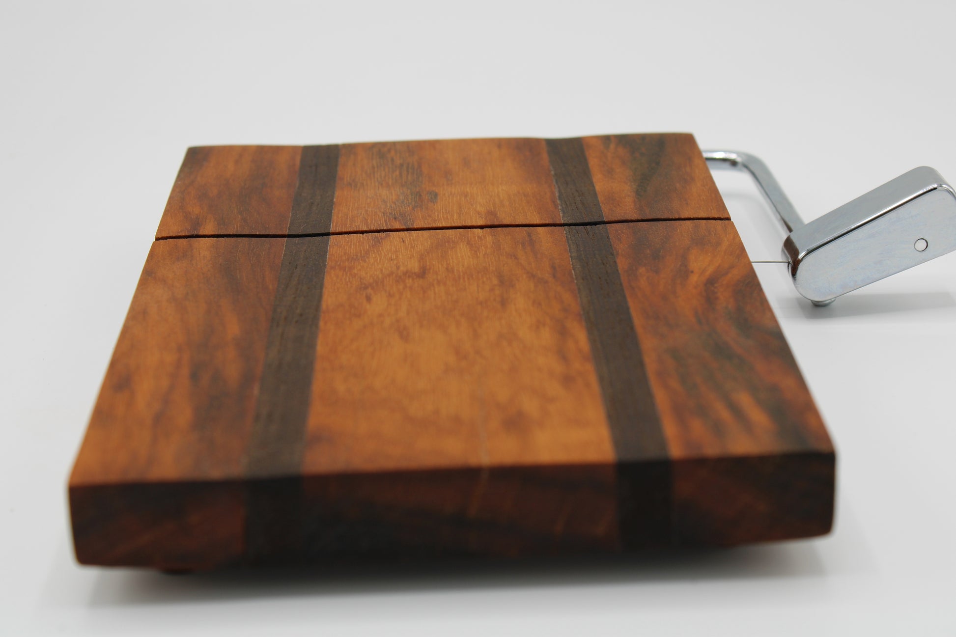 Wooden cheese board with a silver slicer on a white background