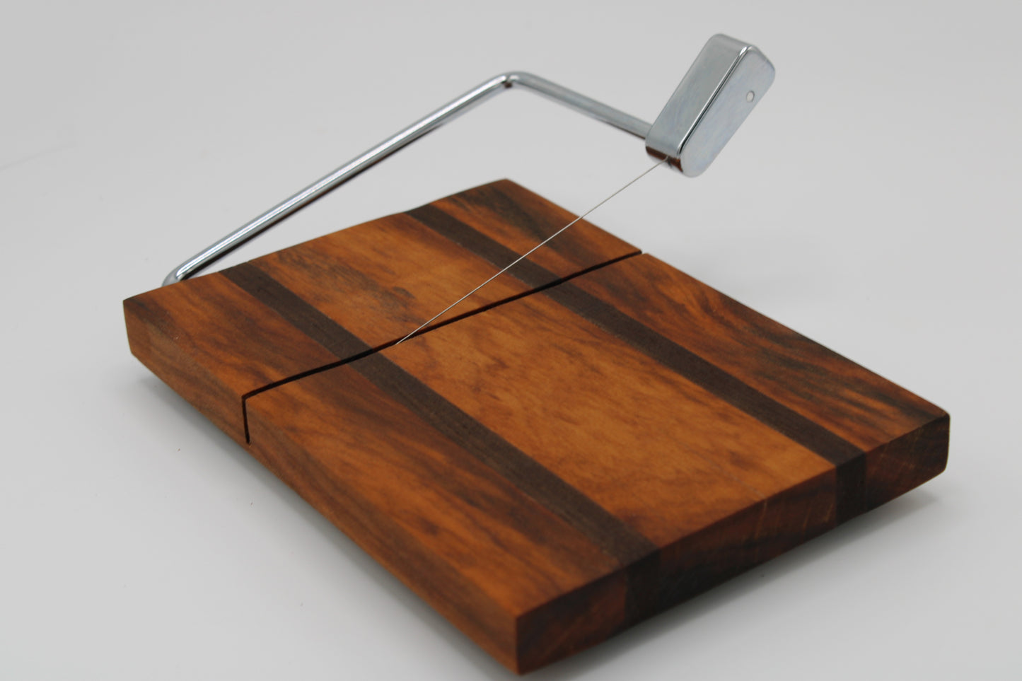 Wooden cheese board with a silver slicer on a white background