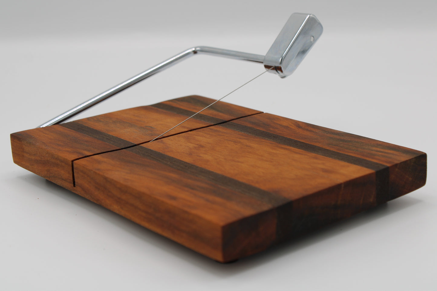 Wooden cheese board with a silver slicer on a white background