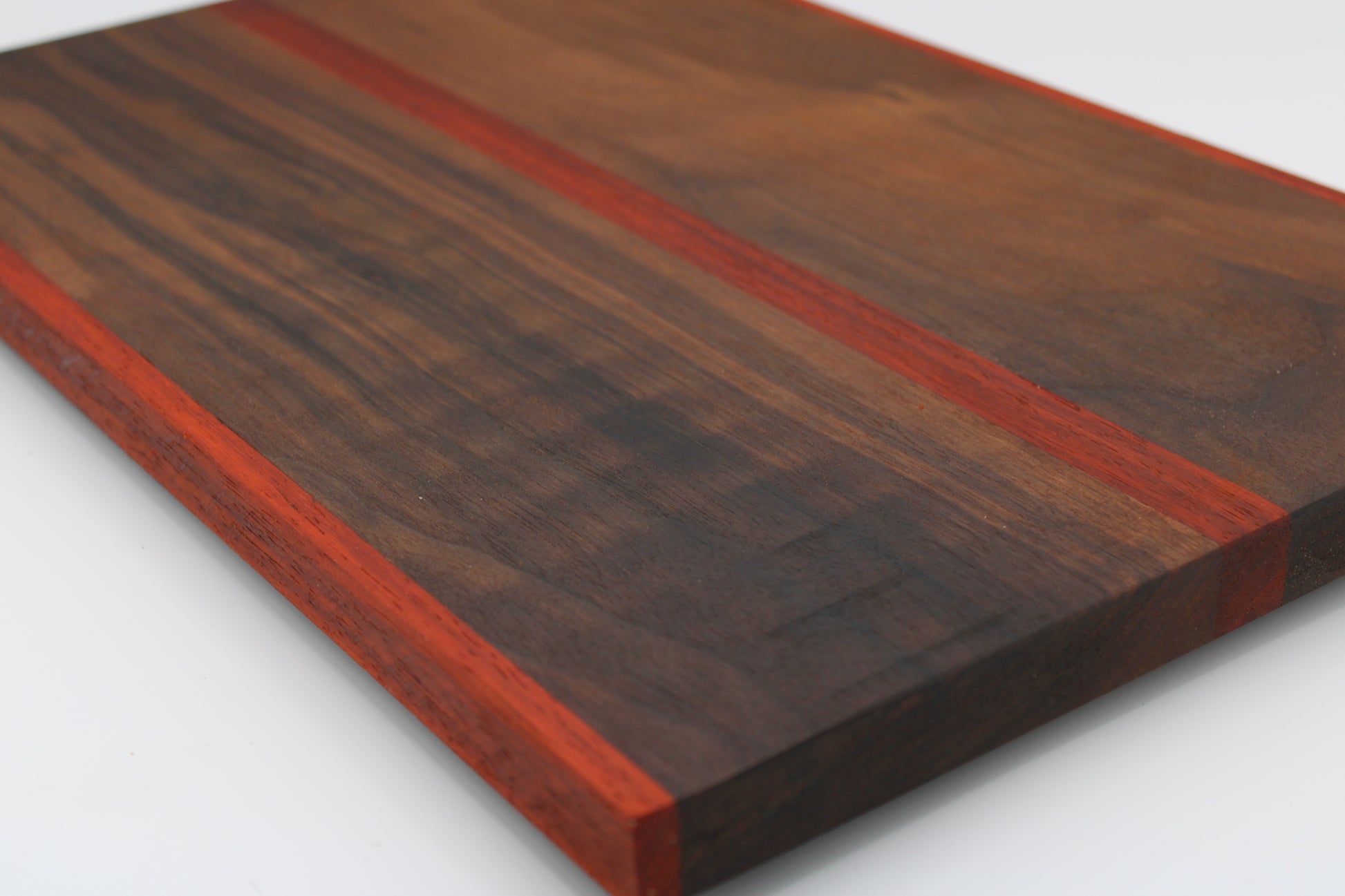 Wooden cutting board with a dark brown and red stripe on a white background