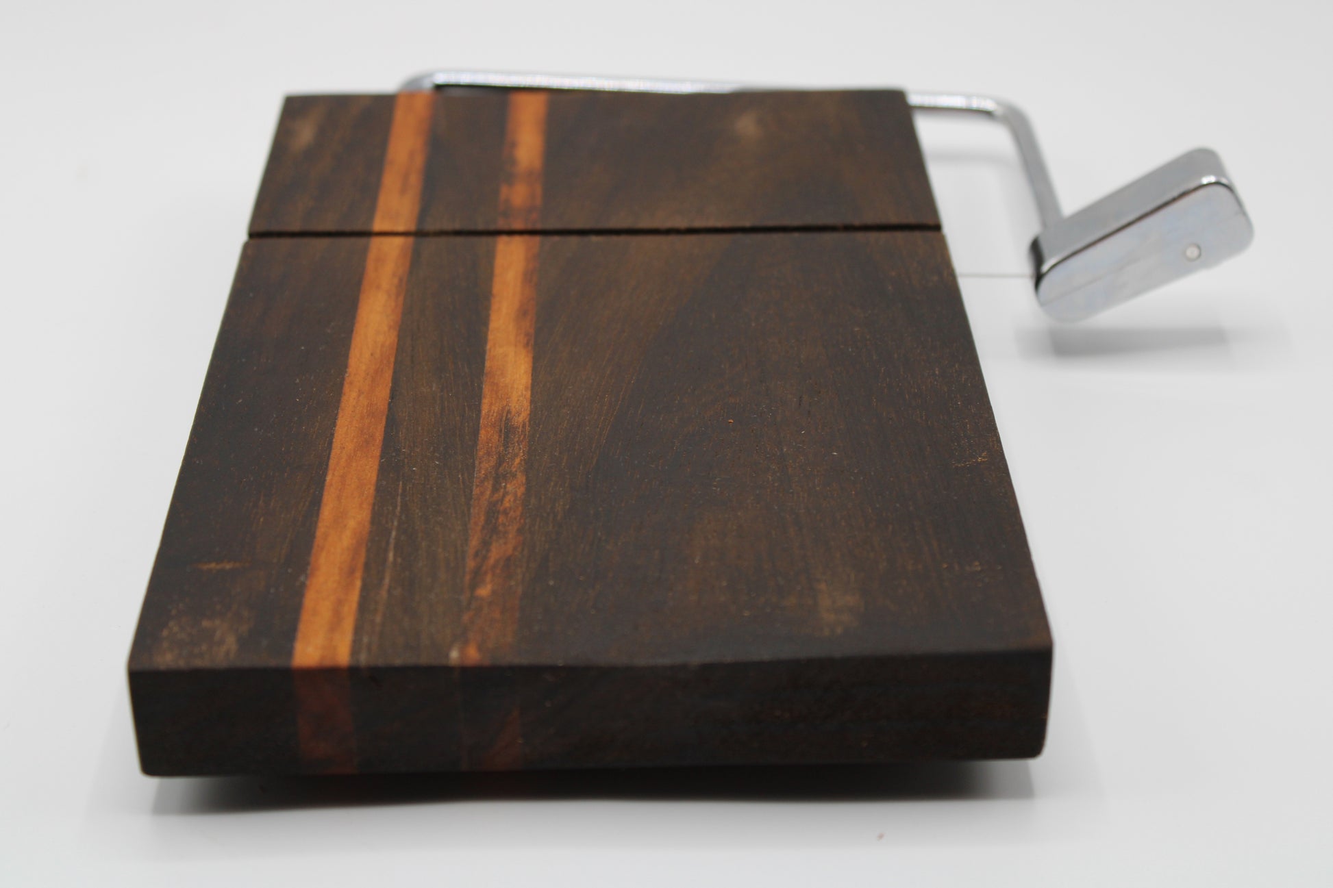 Wooden cheese cutting board with slicer on a light gray background