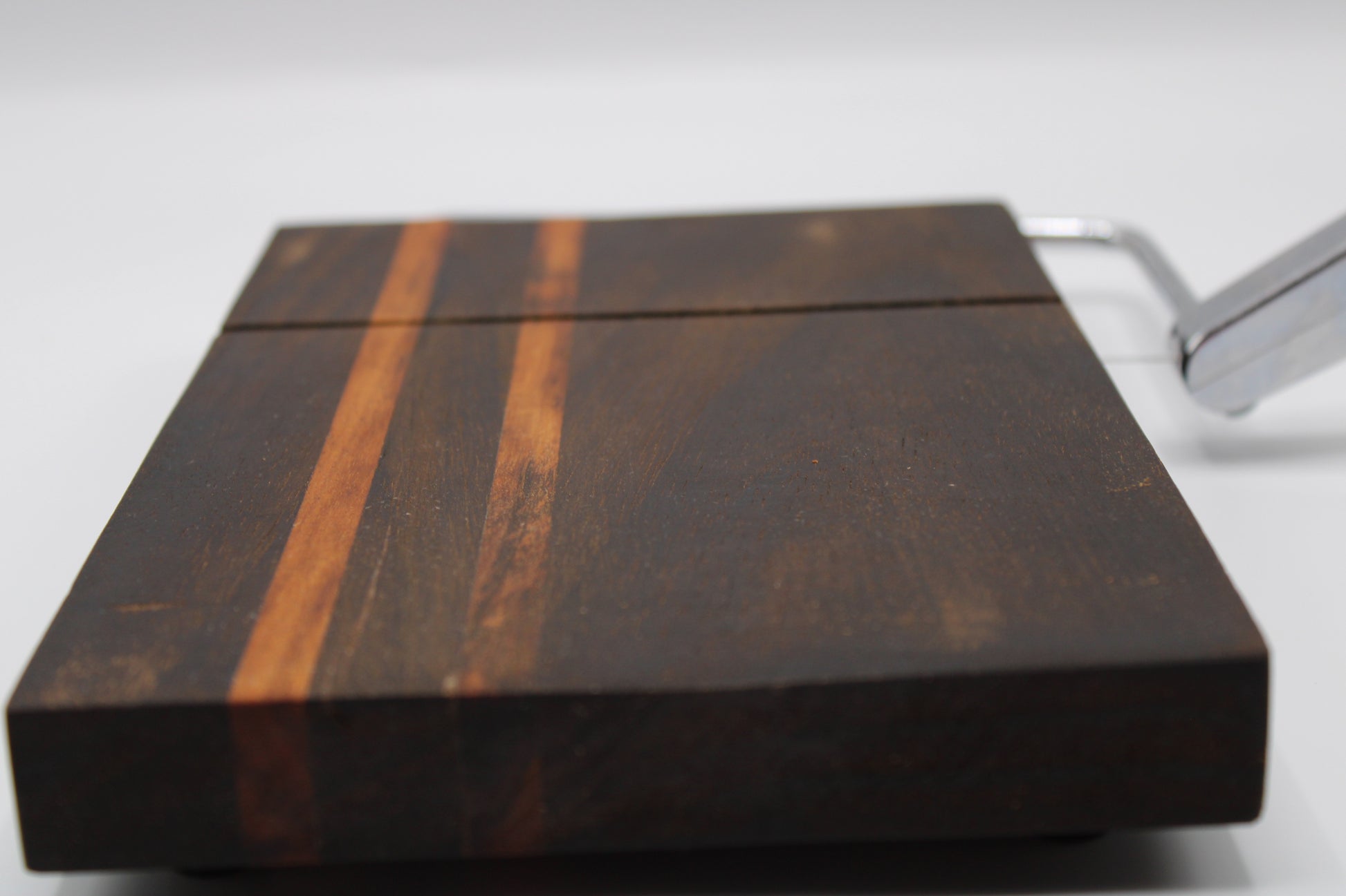 Wooden cheese cutting board with slicer on a light gray background