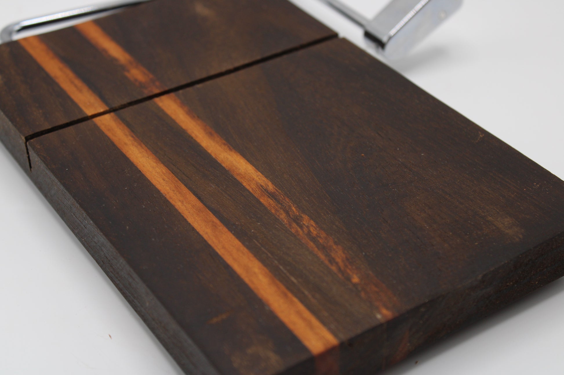 Wooden cheese cutting board with slicer on a light gray background