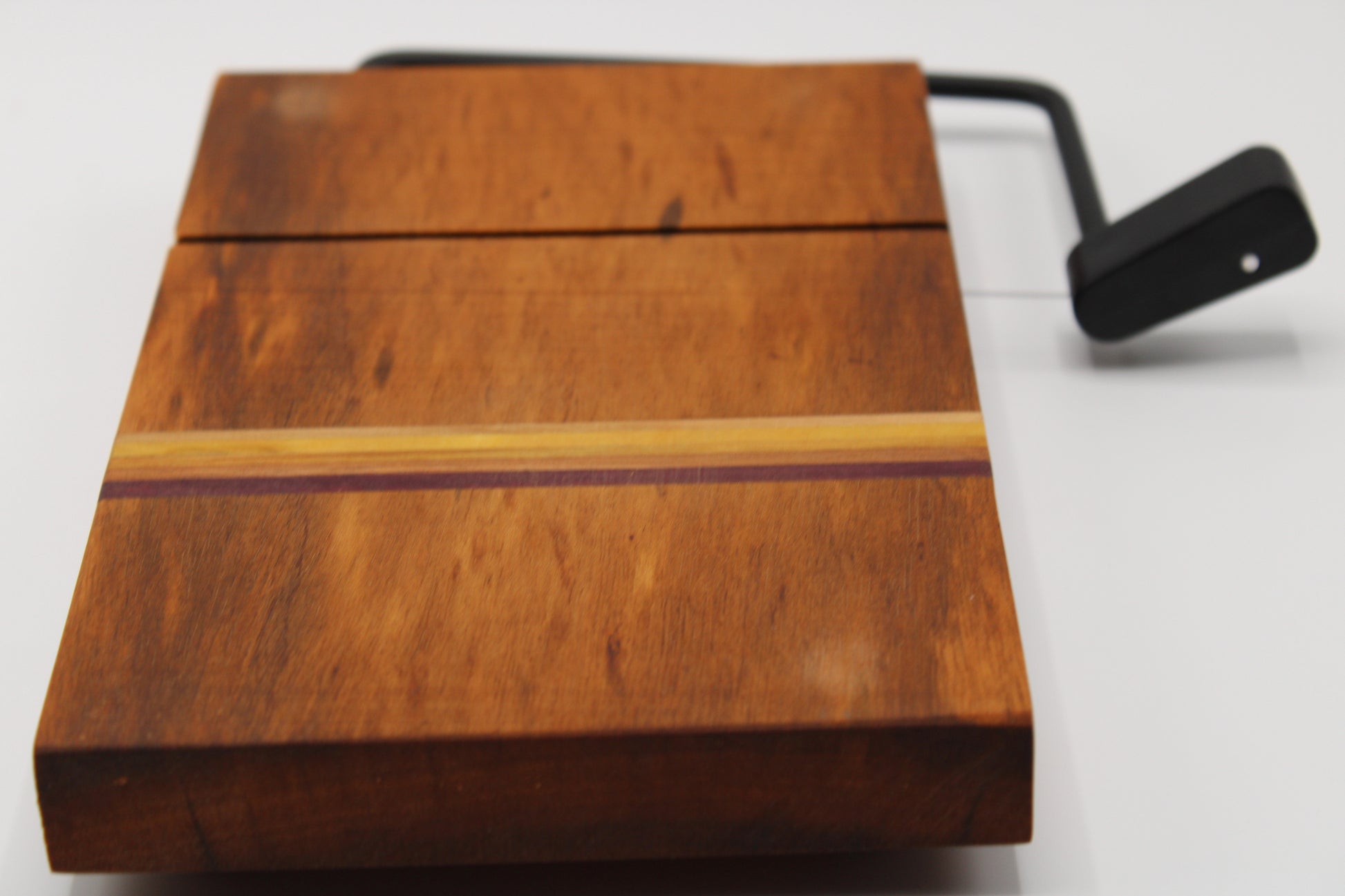 Wooden cheese cutting board with slicer on a light gray background