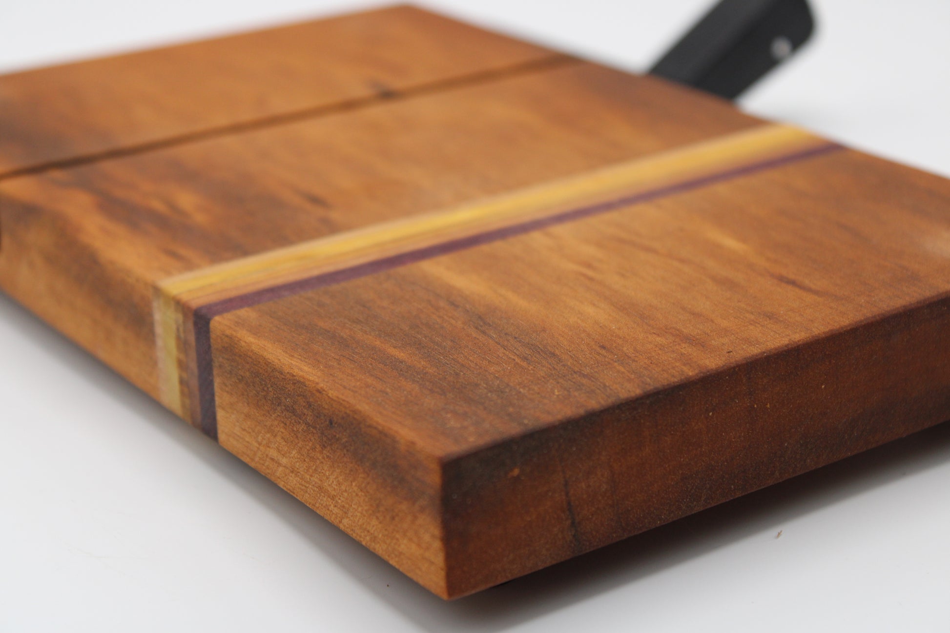 Wooden cheese cutting board with slicer on a light gray background