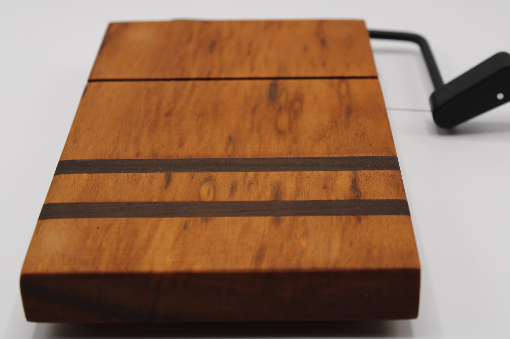 Wooden cheese cutting board with slicer on a light gray background