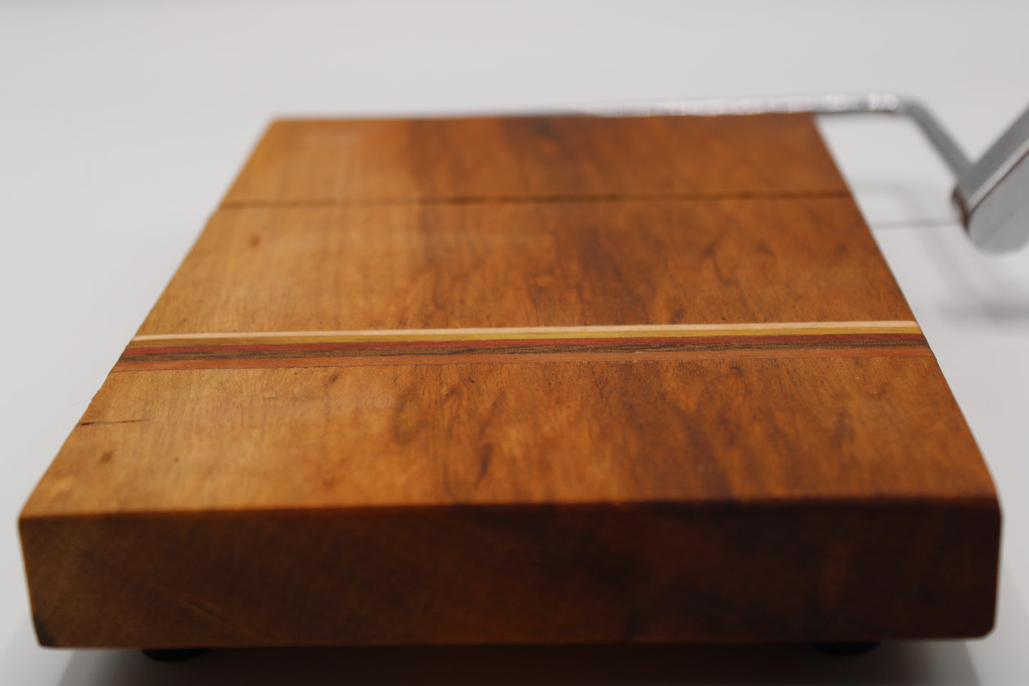Wooden cheese cutting board with slicer on a light gray background