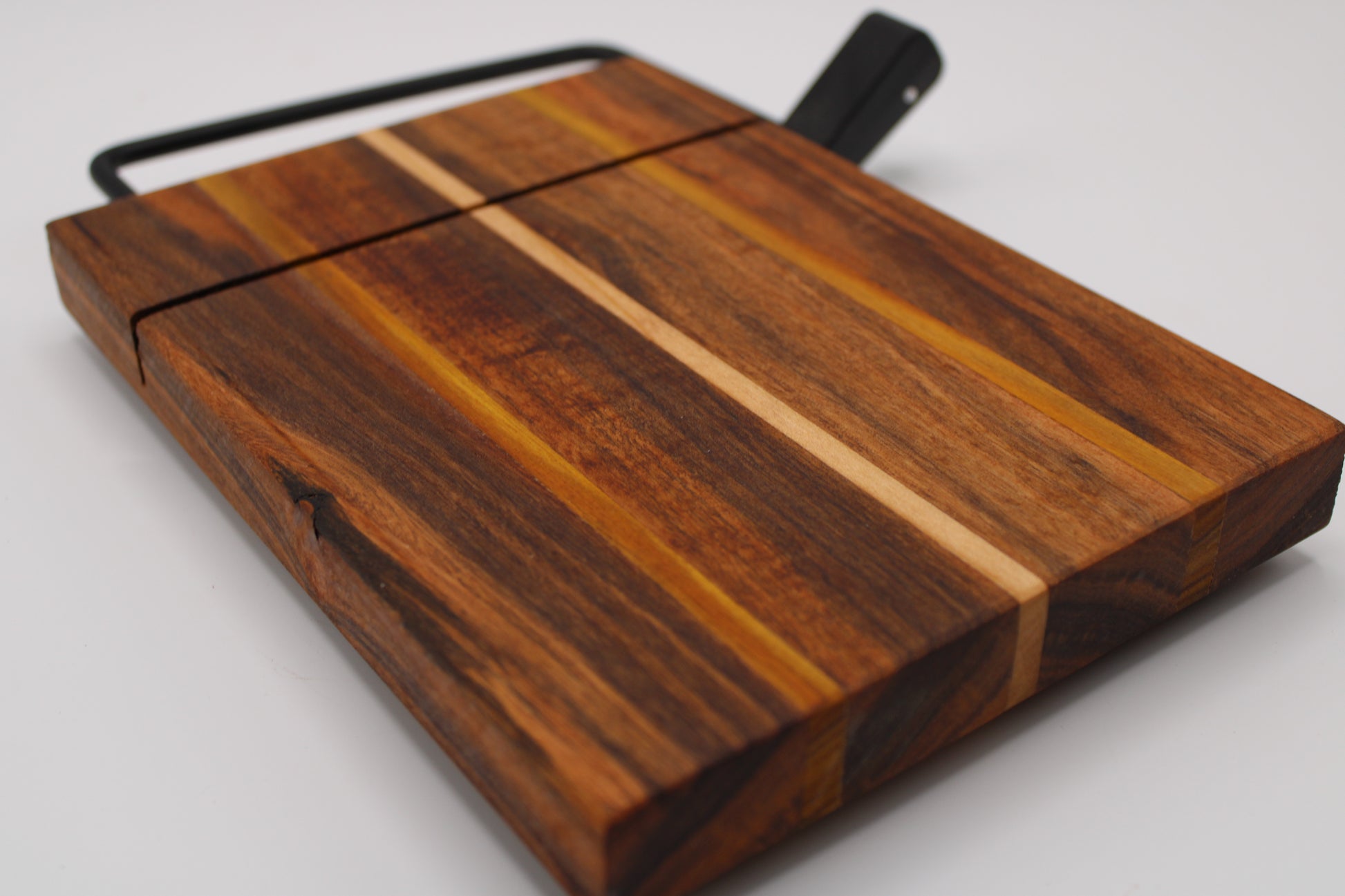 Wooden cheese cutting board with slicer on a light gray background