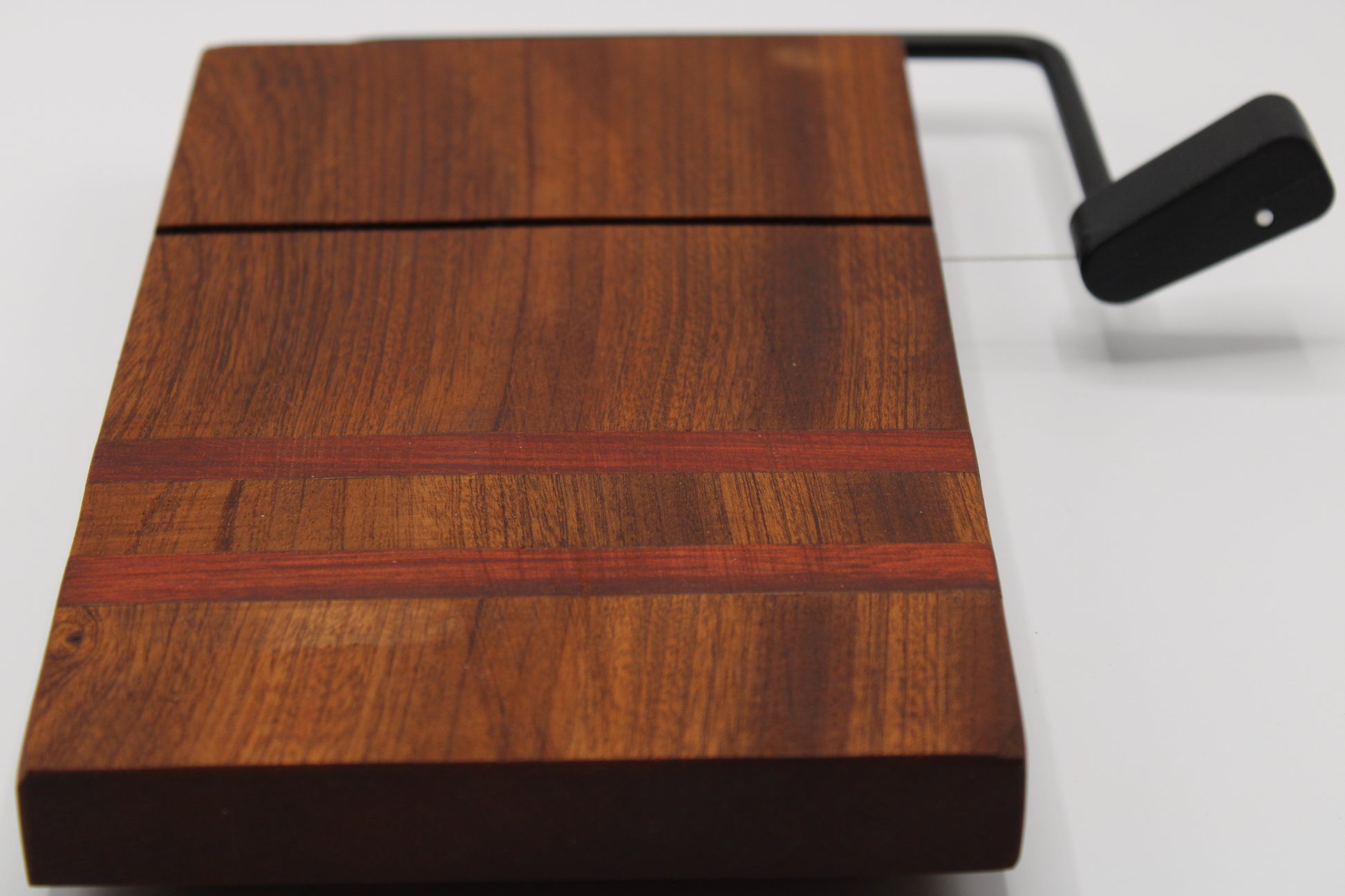 Wooden cheese cutting board with slicer on a light gray background