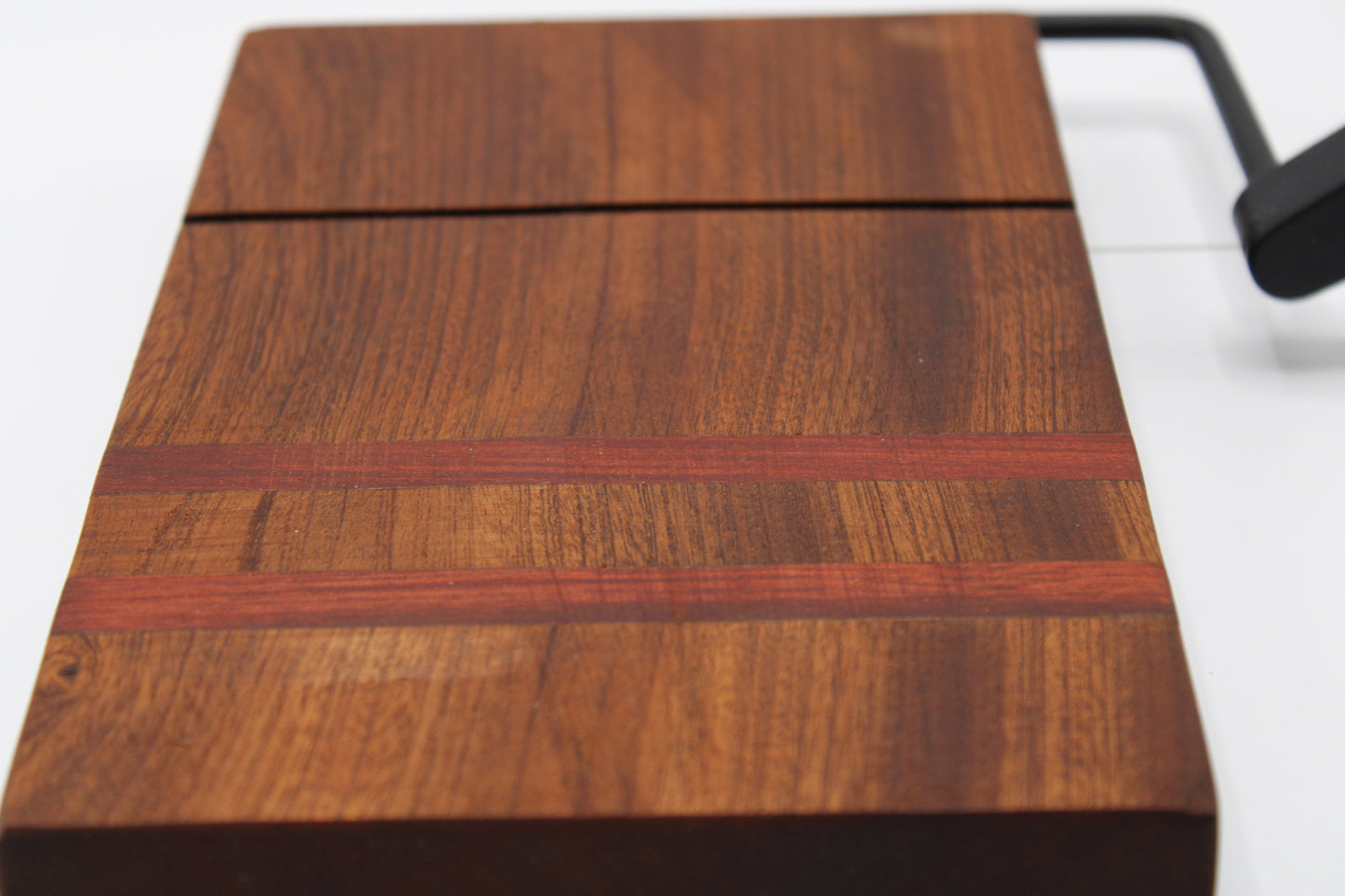 Wooden cheese cutting board with slicer on a light gray background