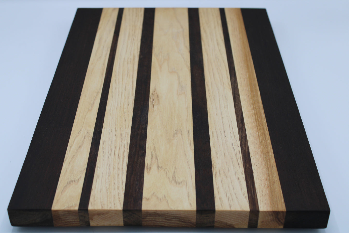 Wooden cutting board with black and light wood stripes on a white background