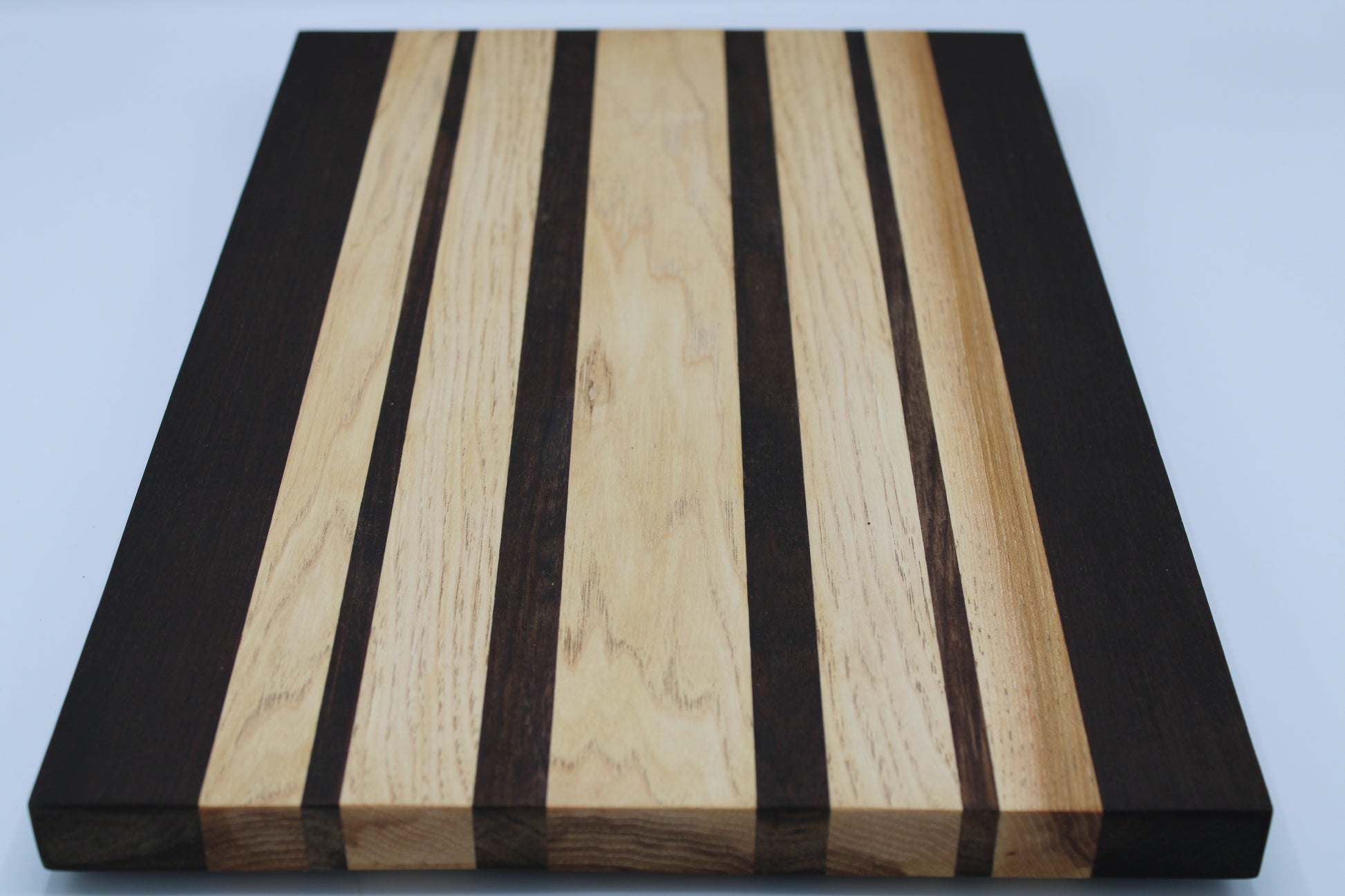 Wooden cutting board with black and light wood stripes on a white background