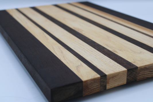 Wooden cutting board with black and natural wood stripes on a white background