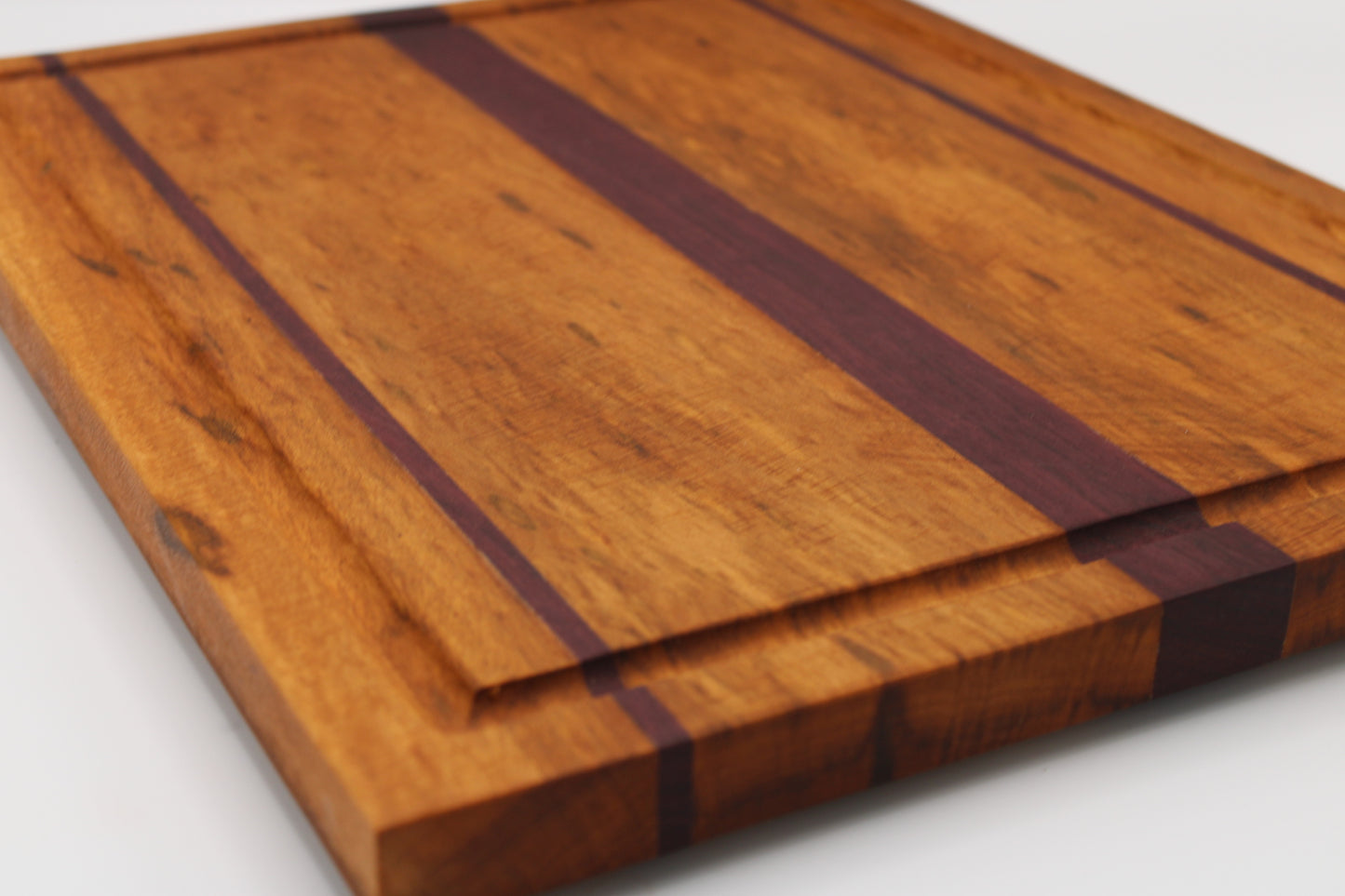 Wooden cutting board with purpleheart inlay on a white background