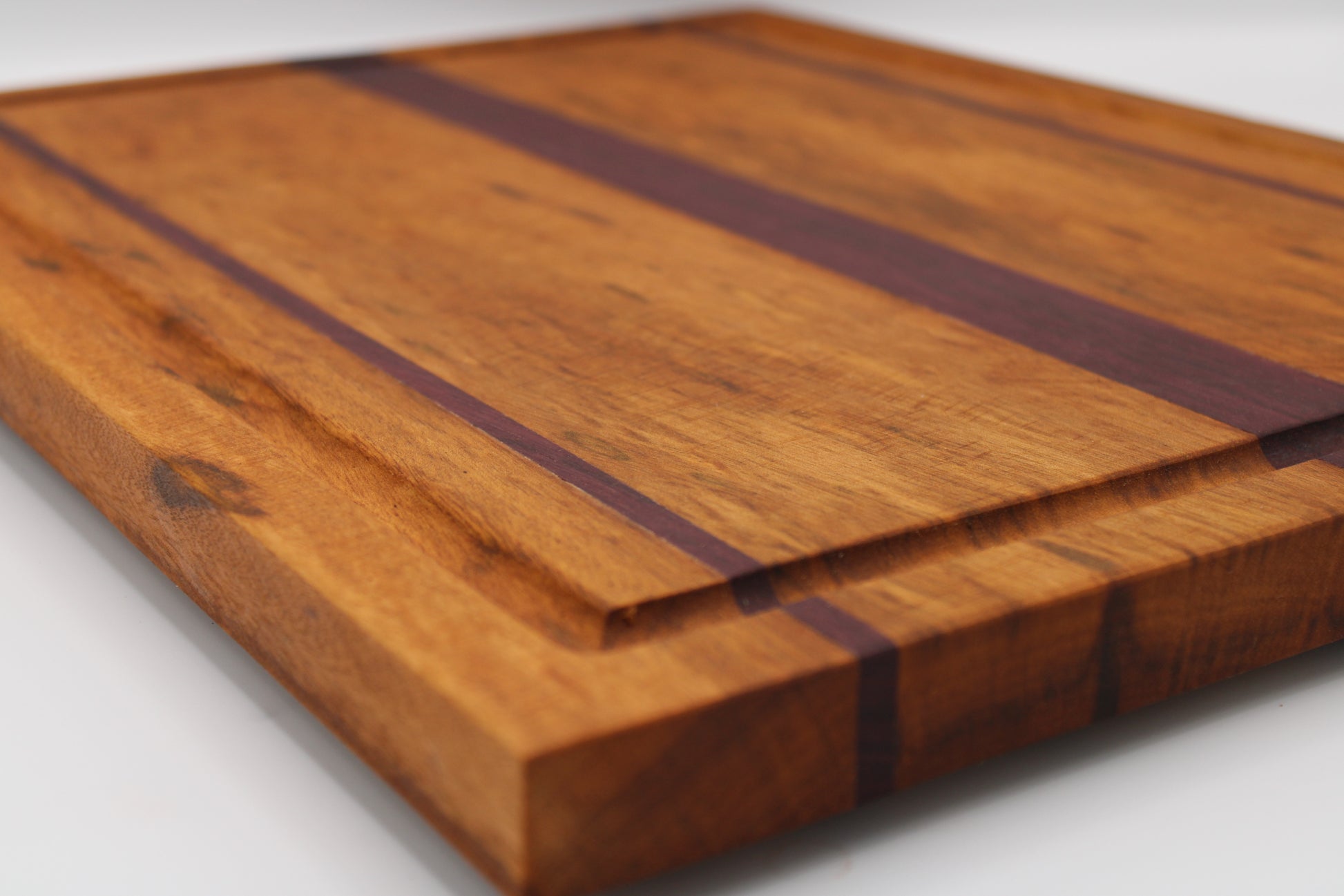 Wooden cutting board with purpleheart inlay on a white background