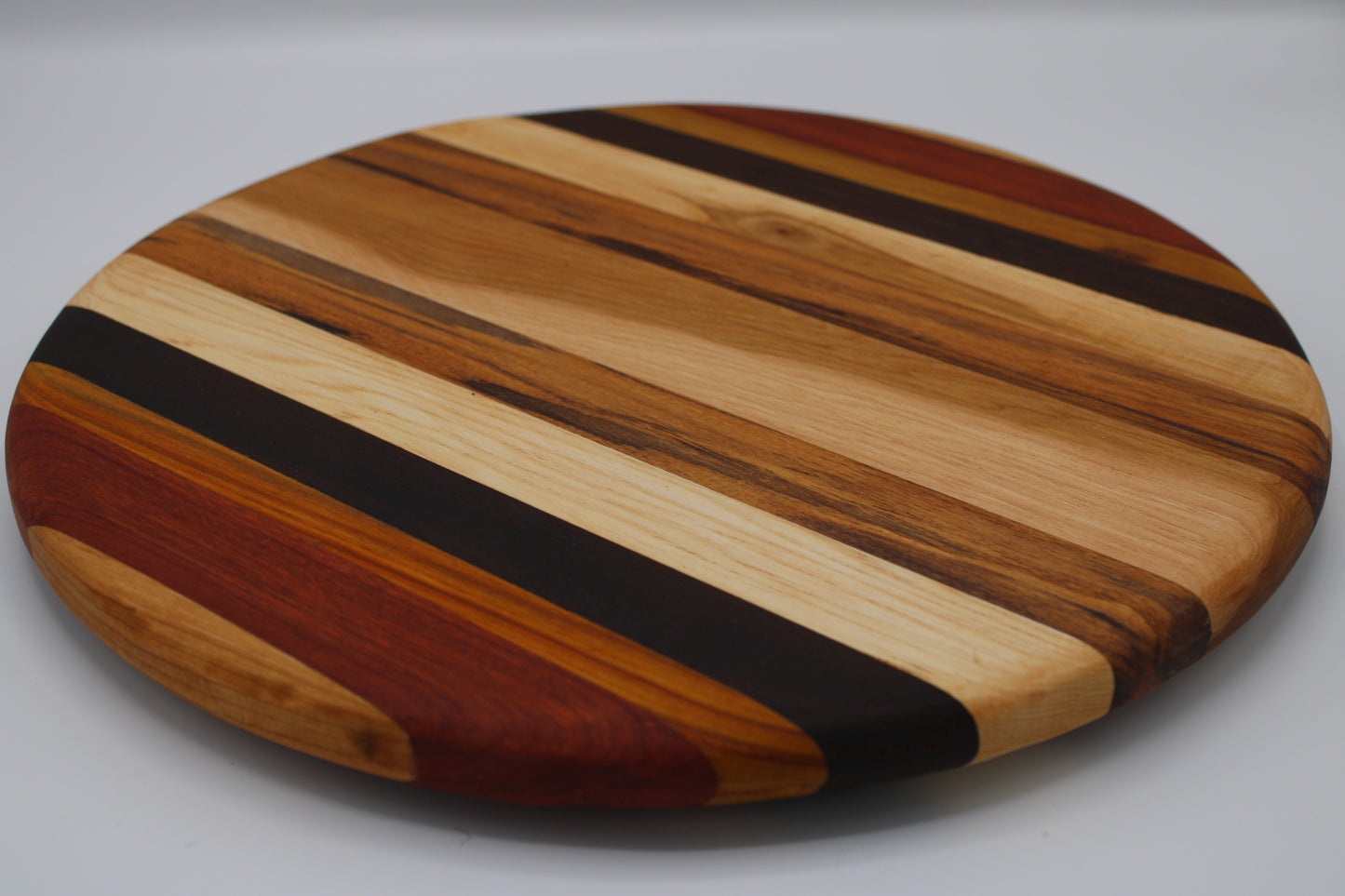 Round wooden cutting board with striped pattern on a gray background