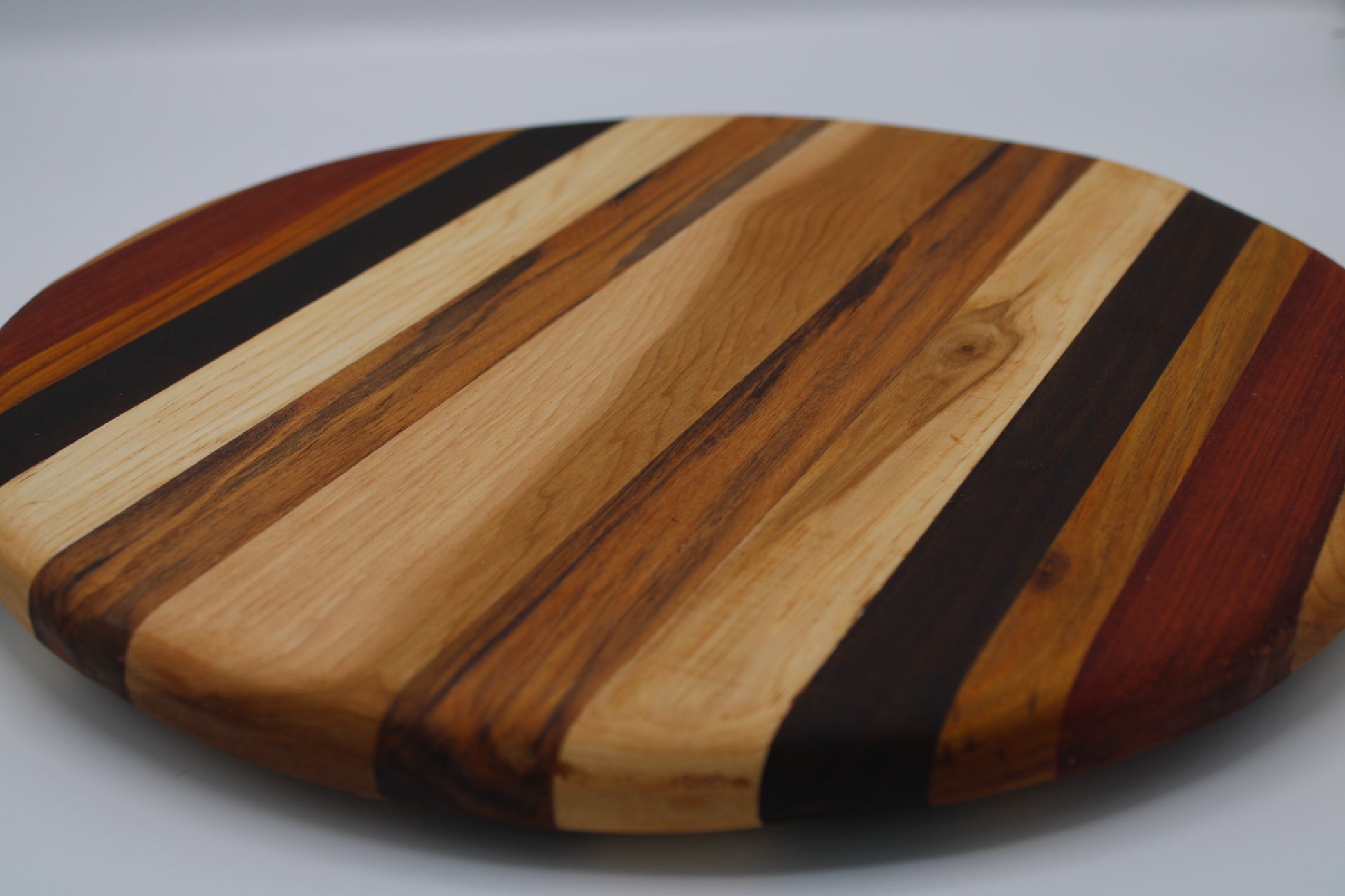 Round wooden cutting board with striped pattern on a gray background