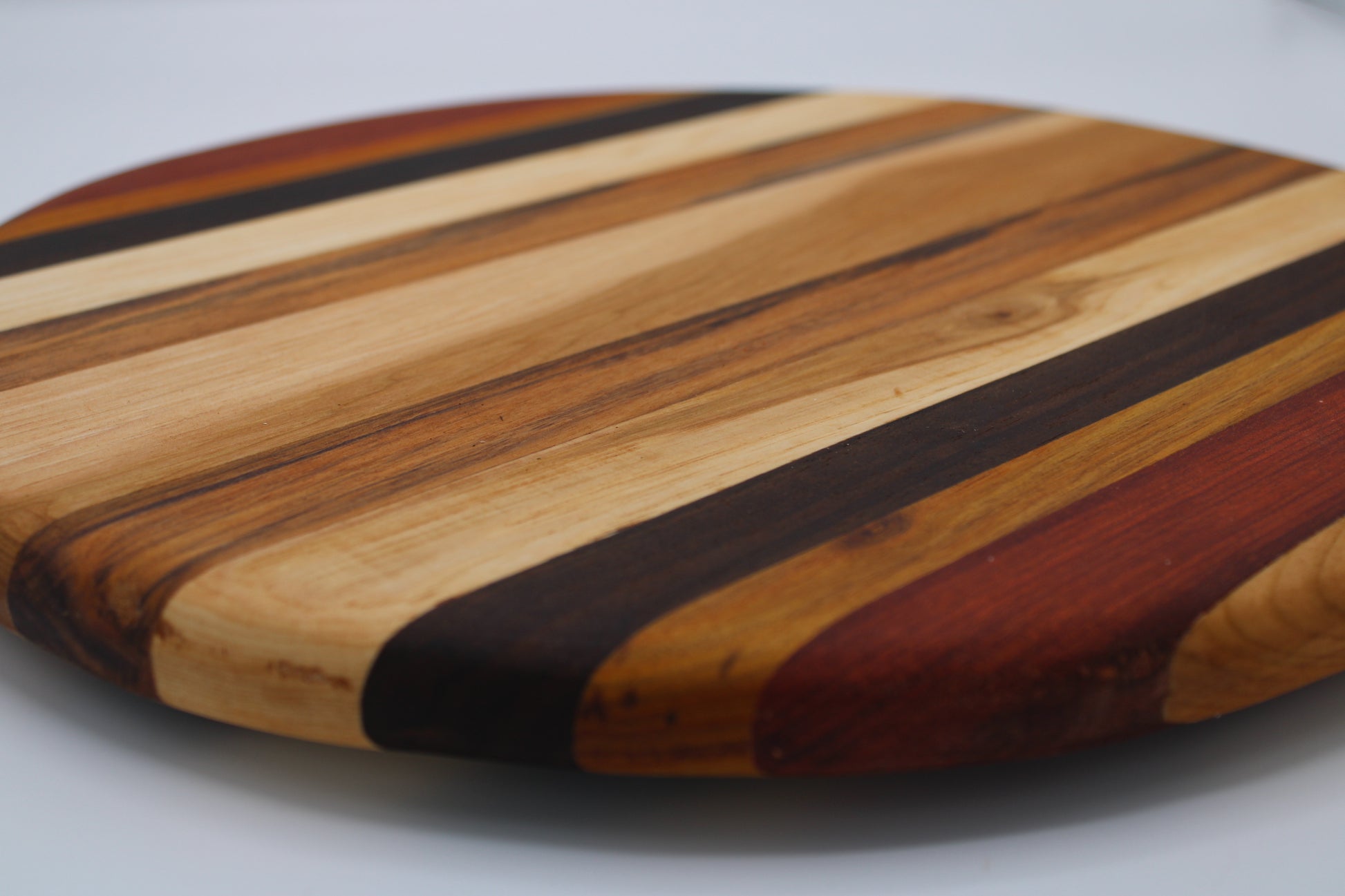 Round wooden cutting board with striped pattern on a gray background