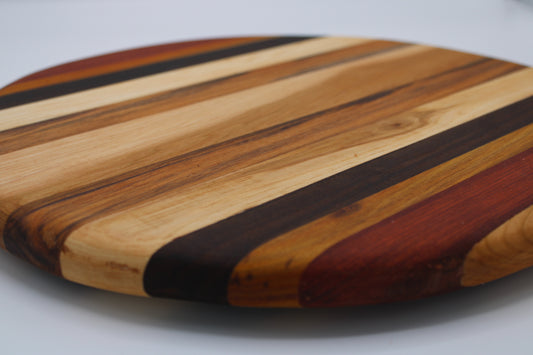 Round wooden cutting board with striped pattern on a gray background