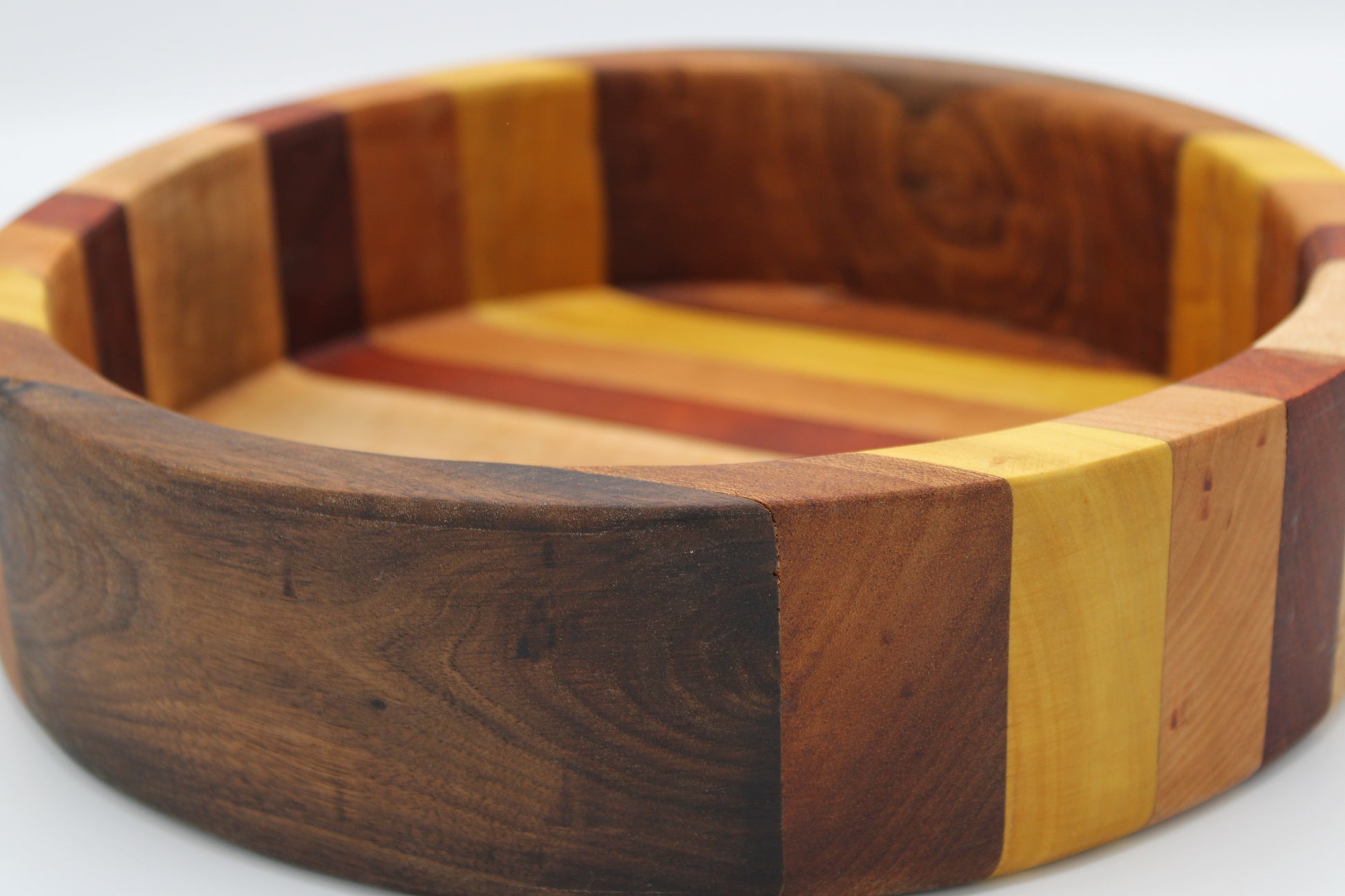 Wooden bowl with multicolored stripes on a white background