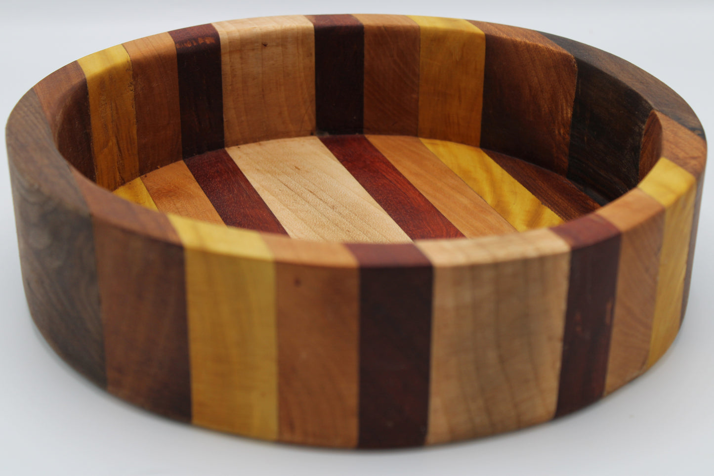 Wooden bowl with multicolored striped pattern on a white background
