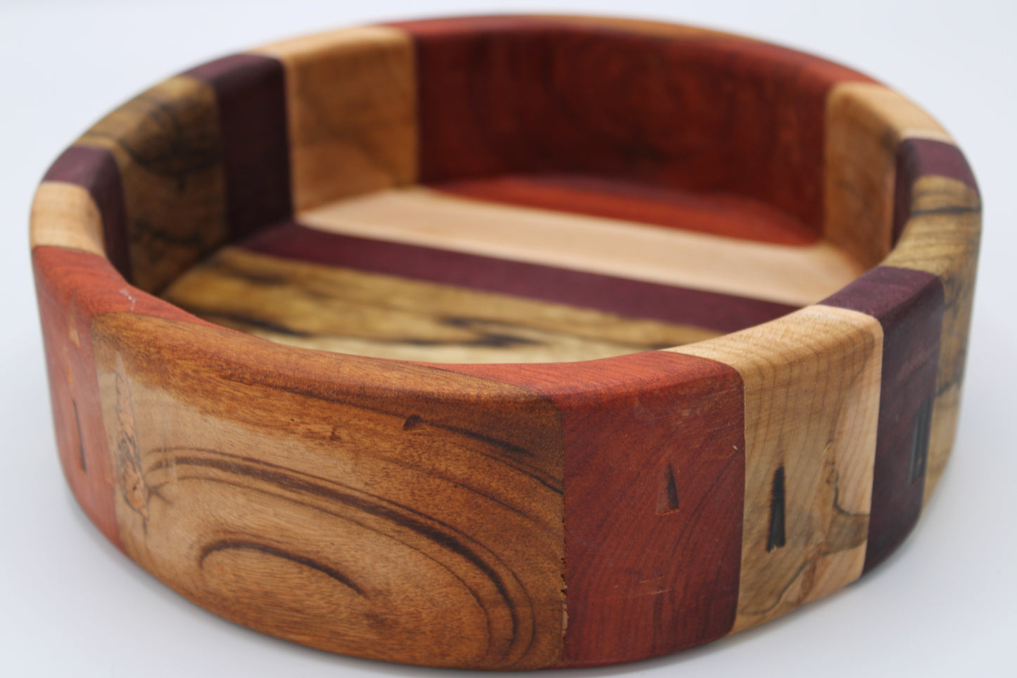 Wooden bowl with a multicolored pattern on a white background
