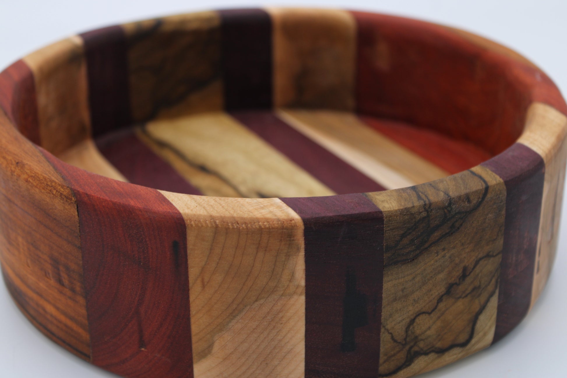 Wooden bowl with multicolored wood strips on a white background