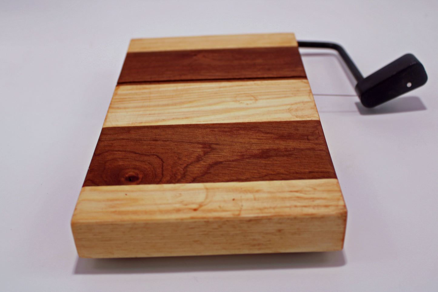 Wooden cheese cutting board with a slicer on a white background