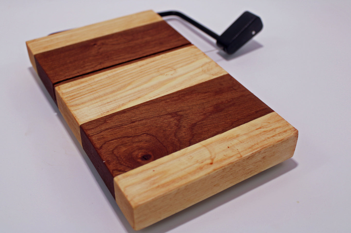 Wooden cheese cutting board with a slicer on a white background