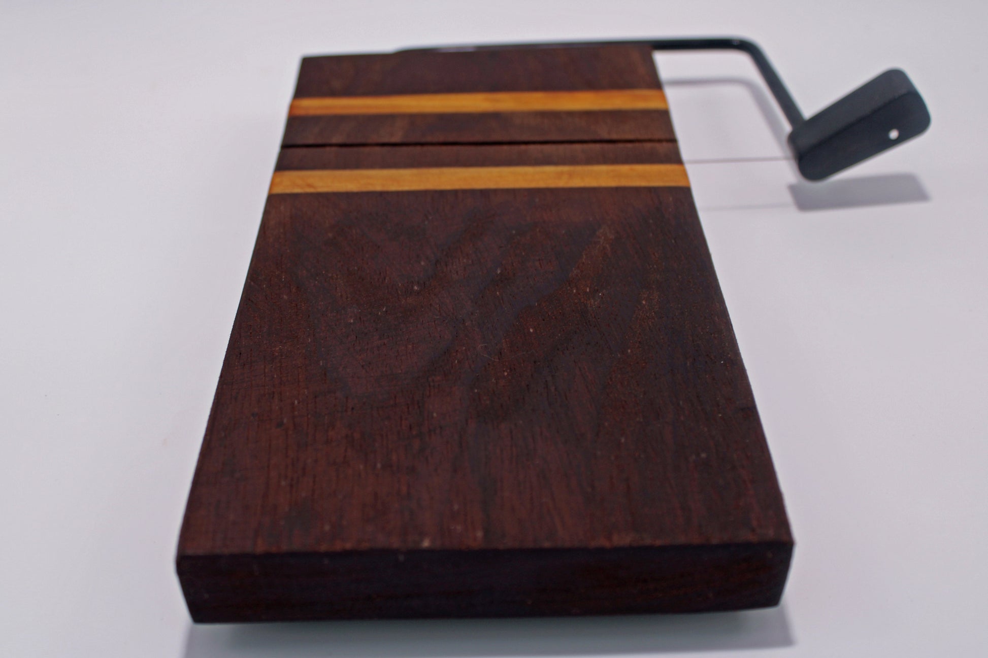 Wooden cheese cutting board with a slicer on a white background
