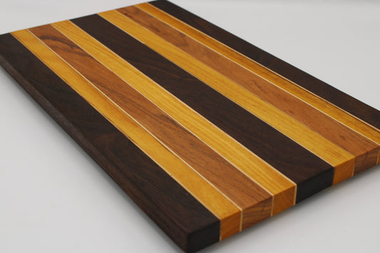 A rectangular wooden board with alternating striped bands of dark brown, medium brown, and light honey-toned wood, photographed on a plain light background.
